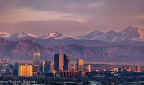 City skyline at sunset with mountains in the background.