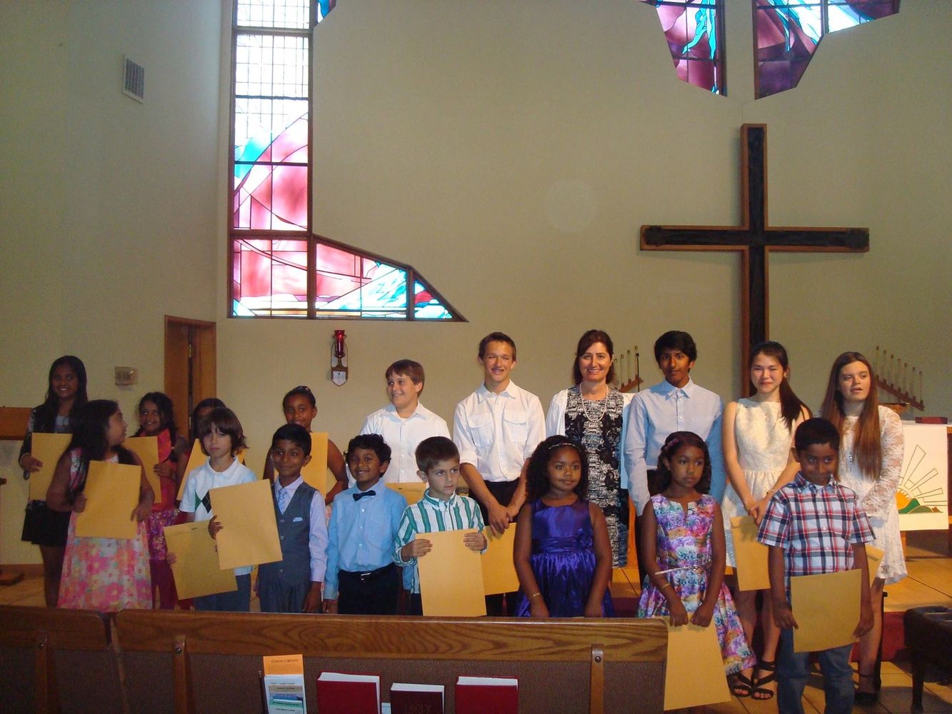 Group of children and a teacher holding certificates in a church.