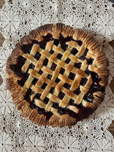 A freshly baked lattice-top pie on a crocheted mat.