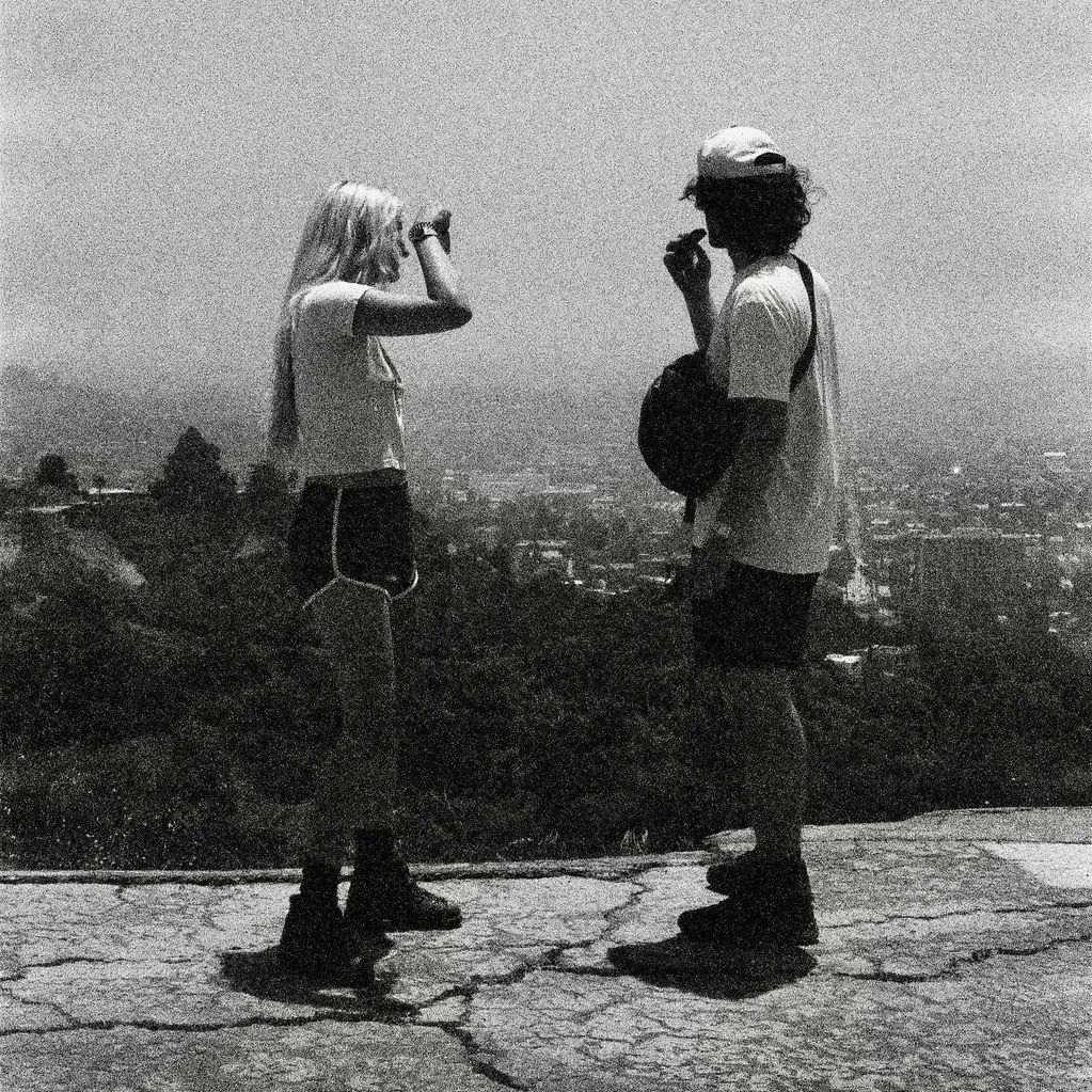 Two people standing and talking on a cracked pavement with a city view.
