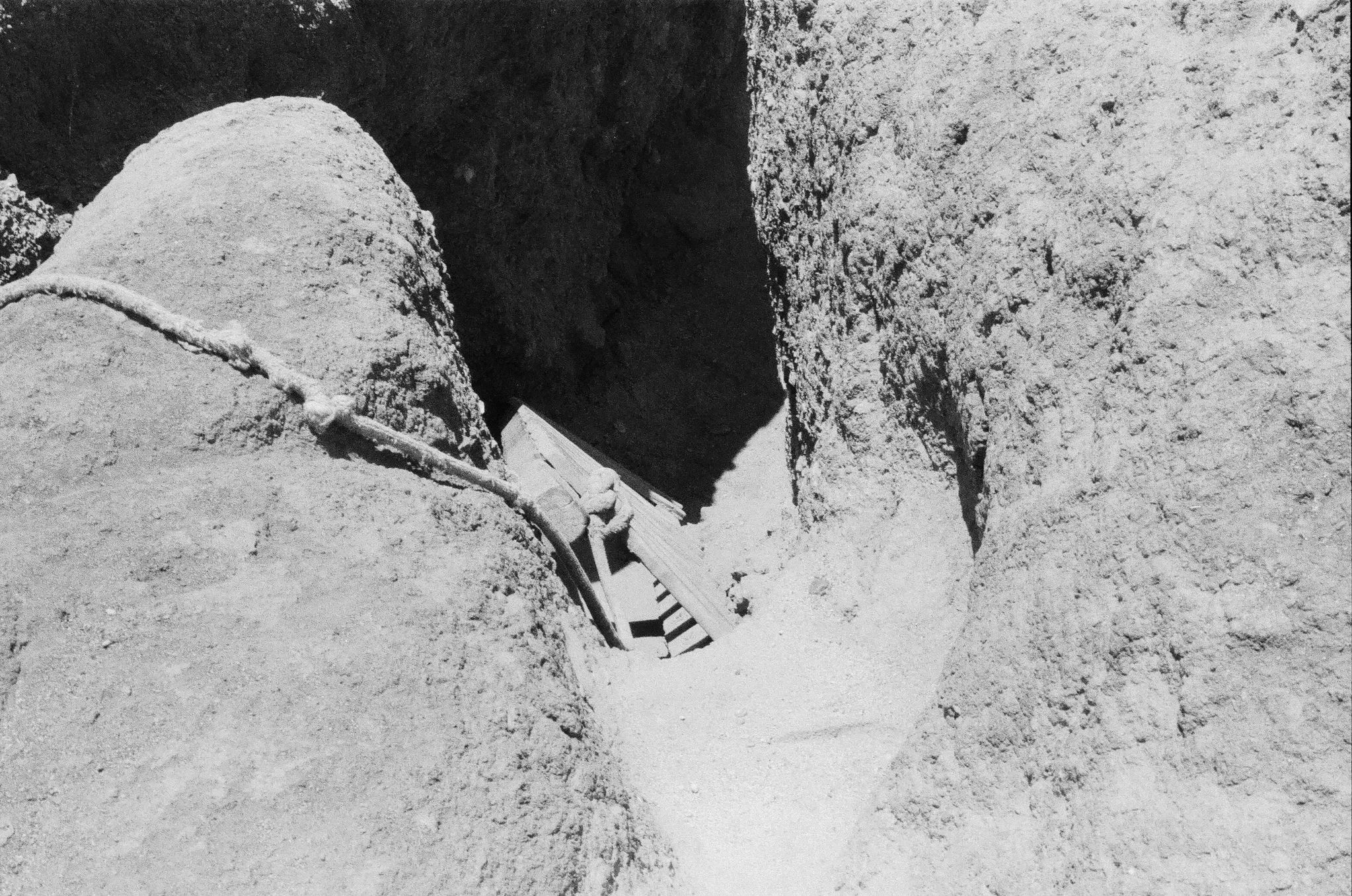 Old wooden ladder leading into a narrow rocky crevice.