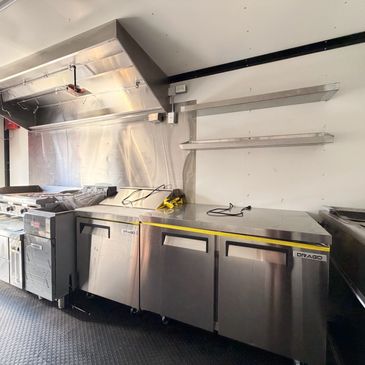 Commercial kitchen setup with stainless steel appliances and shelving.