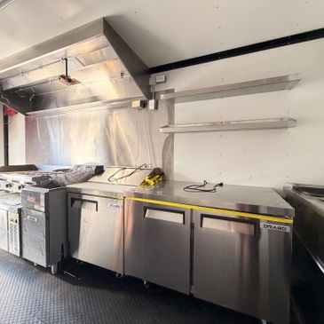 Commercial kitchen setup with stainless steel appliances and shelving.