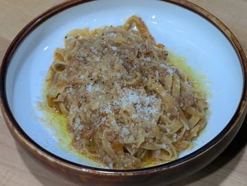 A bowl of pasta topped with grated cheese and sauce.