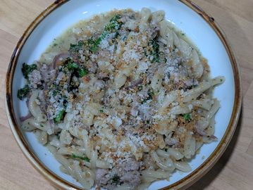 A bowl of creamy pasta with spinach and grated cheese.