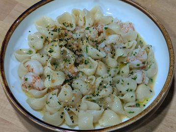 A bowl of shrimp pasta with herbs and garlic sauce.