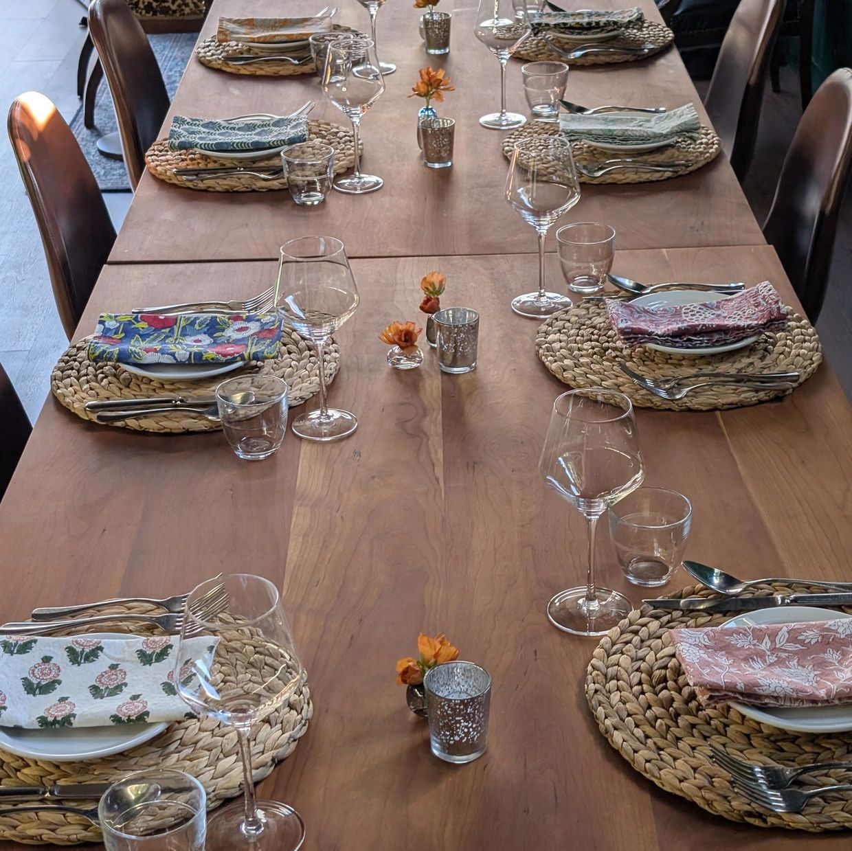 Elegant dining table set with woven placemats and colorful napkins.