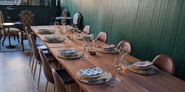 Long wooden table set with plates, glasses, and napkins in a cozy dining room.