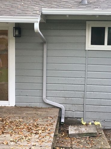 House wall with an oddly bent gutter downspout.