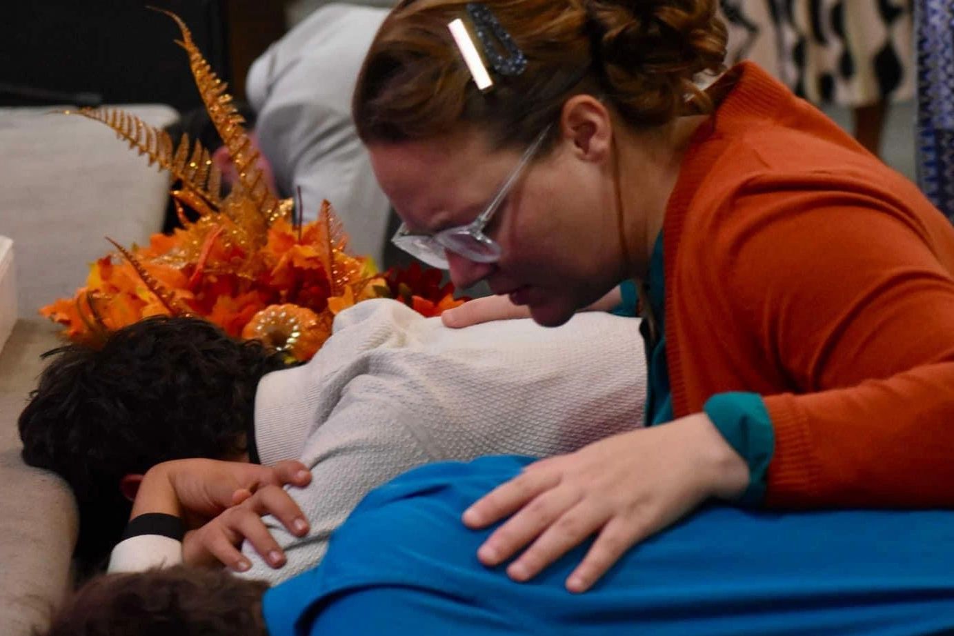 A woman comforting a distressed person lying face down.