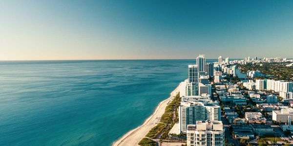 Aerial view of a coastal city with clear blue ocean and sandy beach.