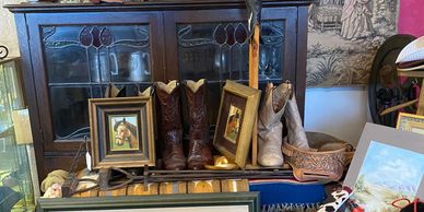 Western-themed display with cowboy boots, horse paintings, and rustic decor.