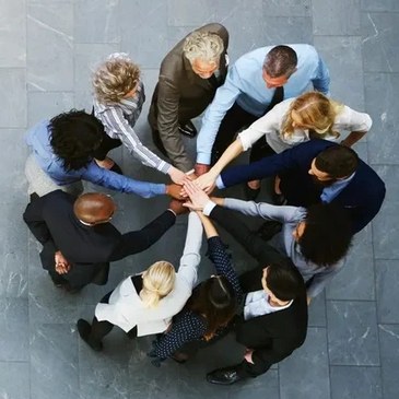 Aerial shot of people in a circle with hands connected in center, making them look like a flower