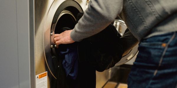 Person loading clothes into a front-loading washing machine.