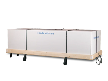 Large white boxes strapped on a wooden cart with wheels, labeled 'Handle with care'.