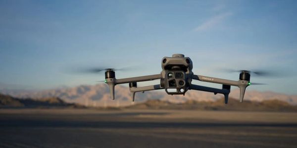 A drone flying over a desert landscape with mountains in the background.