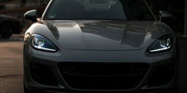 Front view of a gray sports car with headlights on.