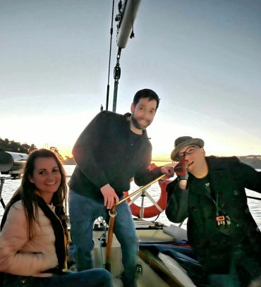 Three friends enjoying a boat ride at sunset, smiling and relaxed.