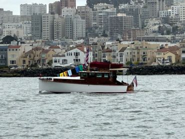 A small boat with colorful flags on a city waterfront.