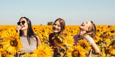 Three girls standing in a sunflower patch