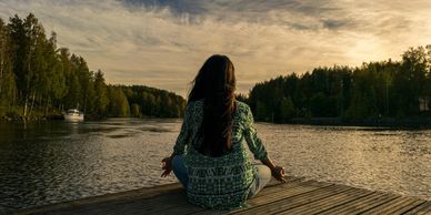 Girl meditating on deck overlooking lake