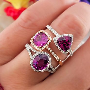 Three elegant rings with purple gemstones and diamond accents on a finger.