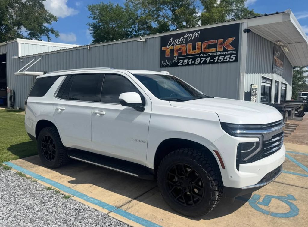 White Chevrolet Tahoe parked outside a custom truck accessories shop.