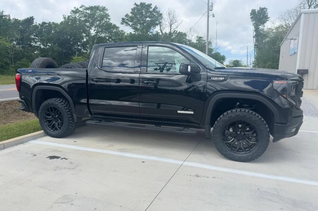 Black pickup truck parked in a lot with off-road tires.