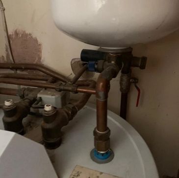 Close-up of expansion vessel and copper pipework on unvented hot water system in need of servicing
