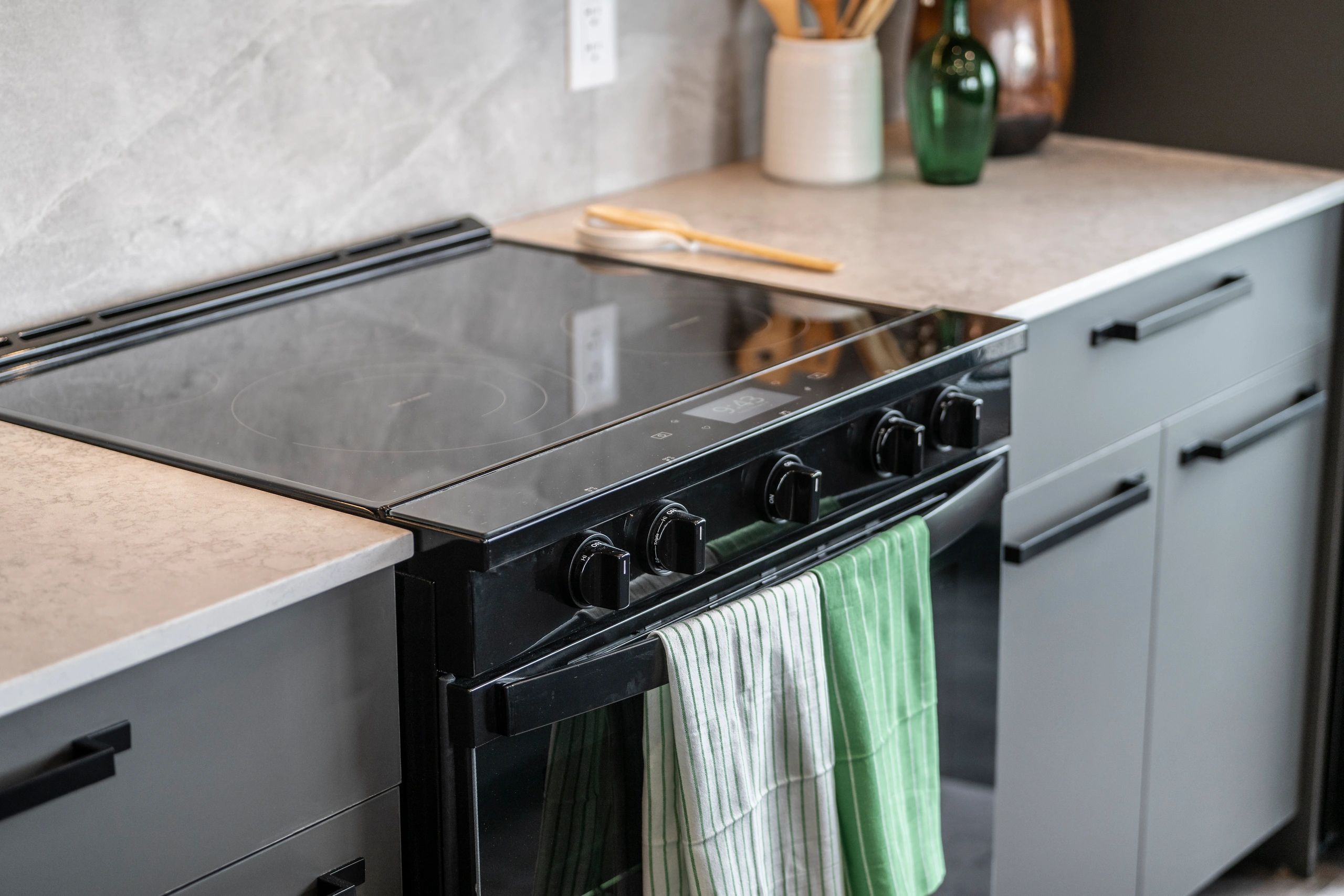 Modern electric stove with striped kitchen towels.