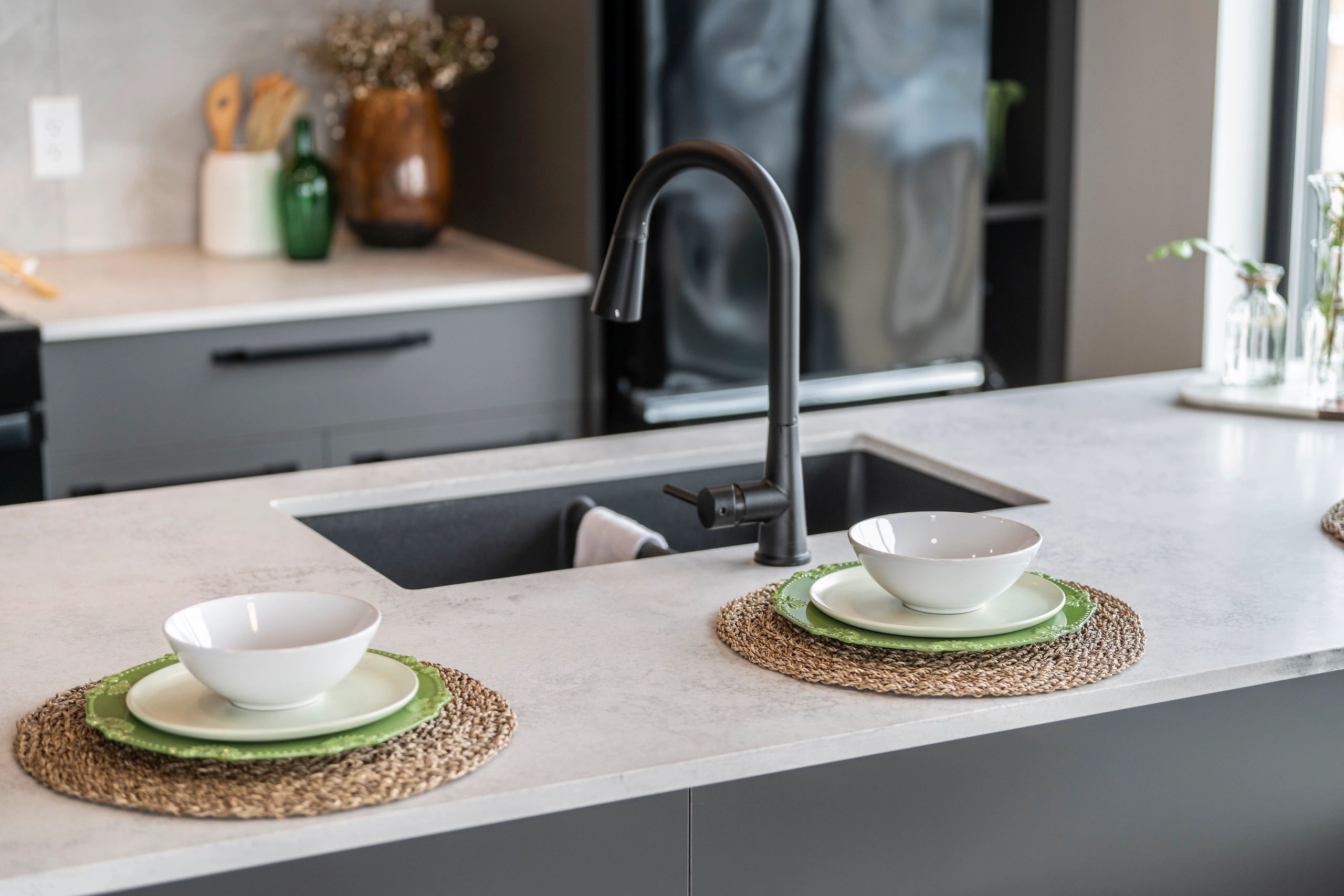 Modern kitchen sink with two place settings on the countertop.