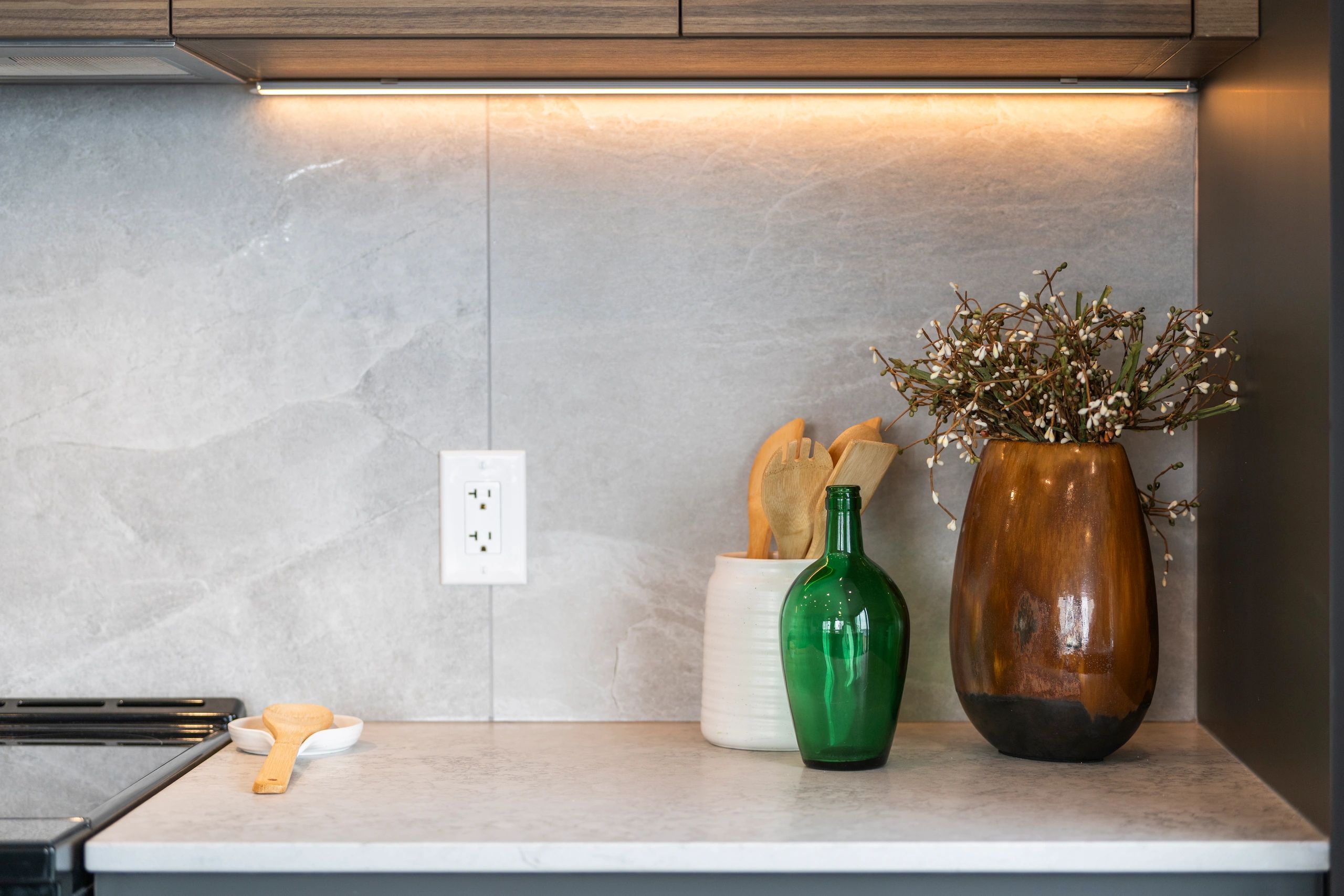 Modern kitchen counter with utensils and decorative vases.