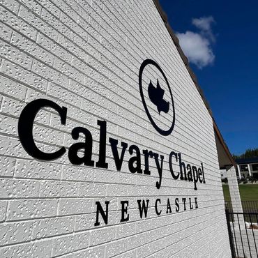 Calvary Chapel Newcastle sign on a brick wall under blue sky.