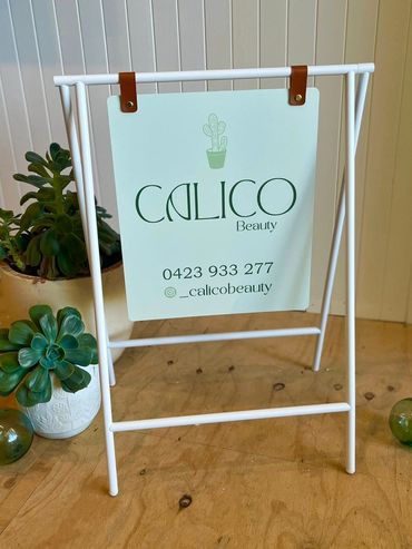 Sign for Calico Beauty with succulents.