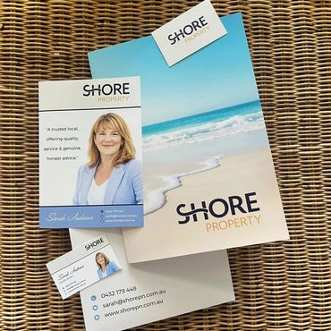 Shore Property real estate marketing materials on wicker table.