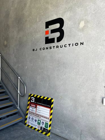 BJ Construction logo painted on a concrete wall near stairs.