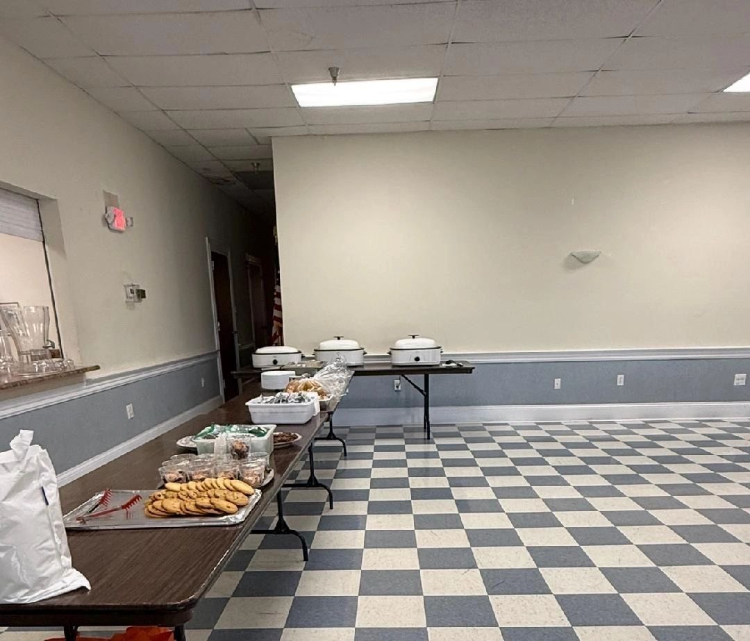 Buffet setup with cookies and covered dishes in a checkered floor room.