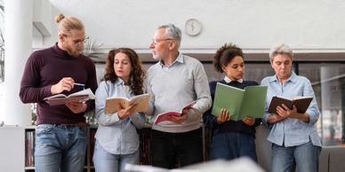Group of diverse adults reading books together indoors.