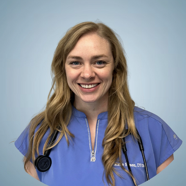 Smiling female veterinarian in blue scrubs with a stethoscope.