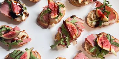 Appetizers with figs, ham, and arugula on bread.