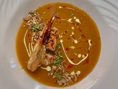 Creamy shrimp bisque with garnishes and drizzles.