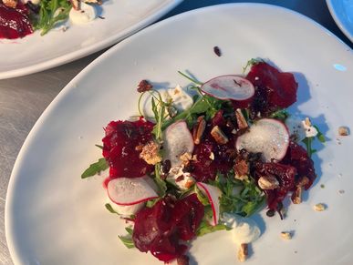 Beet and radish salad with nuts on white plates.