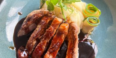 Sliced steak with mashed potatoes and vegetable garnish.