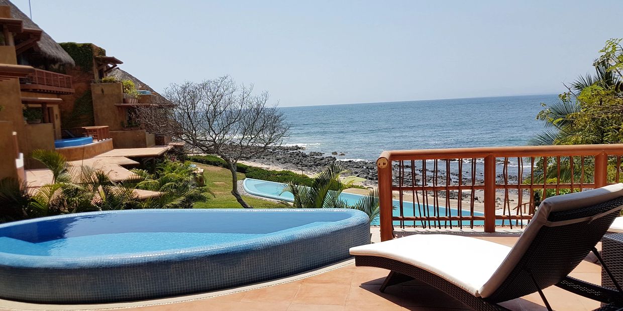 Oceanfront resort in Troncones with a pool and lounge chair overlooking the sea.