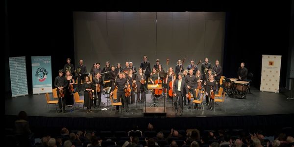 Orchestra and conductor taking a bow on stage after performance.
