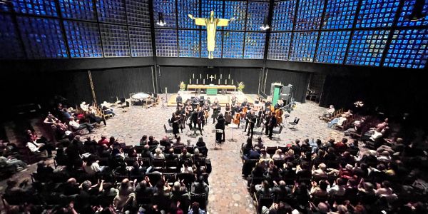 Orquesta tocando en una iglesia moderna con público.