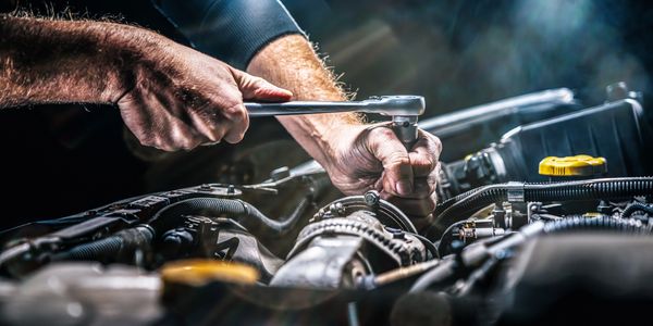 Hands using a wrench to repair a car engine.