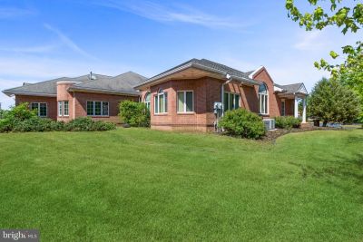 Brick house with large green lawn under blue sky.