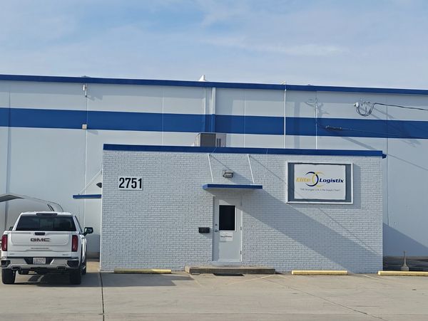 Small logistics office with a white truck parked outside under a clear sky.
