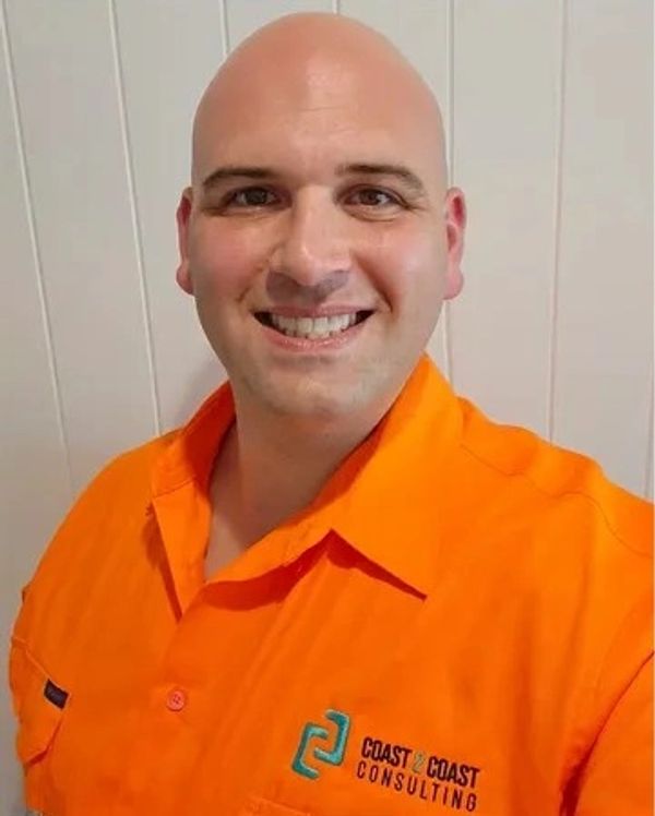 Smiling man in bright orange Coast 2 Coast Consulting shirt.